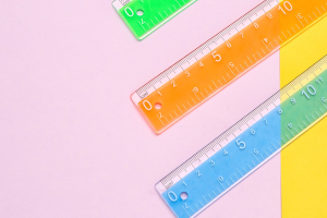 three colorful rulers on a pink and yellow background