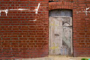 A wooden door covered in drawings sit in the middle of a red brick wall