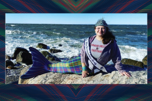 Sonja Michaluk in a mermaid tail poses on a rock overlooking the ocean