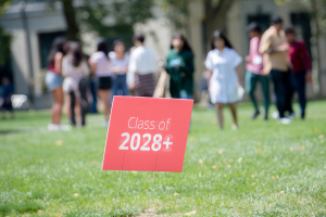 Class of 2028+ lawn sign with people in the background